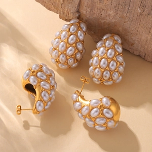 Vintage gold teardrop earrings with white pearls on a textured background for women