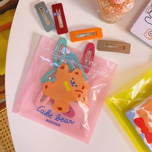 Colorful metal snap hair clips set with cute bear packaging on a white desk