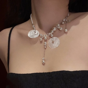 Detail of elegant shell pearl tassel necklace on woman's collarbone with silver chain