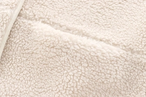 Detailed macro shot of warm creamy white teddy fleece fabric texture and soft wool fibers