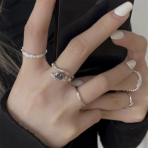 Close-up of a hand wearing 925 sterling silver rings with iridescent gems and textured bands