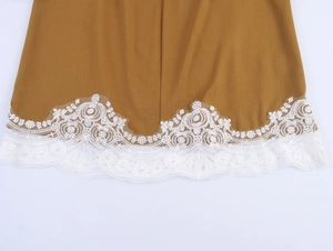 Detail of elegant lace patchwork on ginger long sleeve blouse hem with intricate white patterns