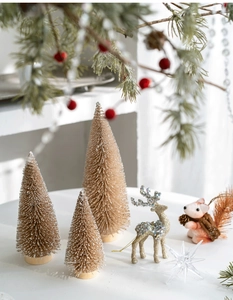 Mini beige sisal Christmas trees and gold glitter reindeer on a white tabletop display