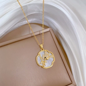 Macro detail of bird and bamboo pendant on gold necklace with white shell inlay