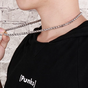 Gros plan d'un collier pour homme en acier inoxydable argenté avec maille carrée perlée