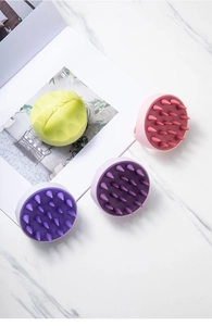 Top view of four colorful silicone scalp massage brushes on white marble background