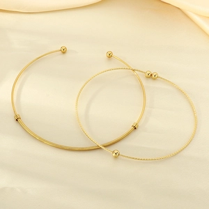 Detail of gold twisted wire collars and woven neck rings on beige silk fabric