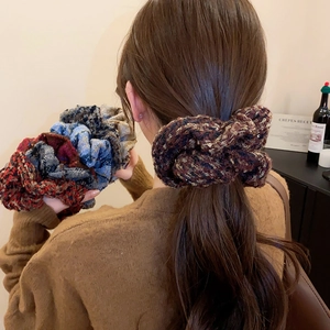 Détail de chouchous tricotés à carreaux marron et bleu sur les cheveux du modèle