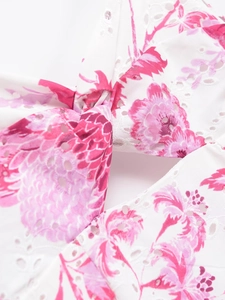 Vue détaillée de la broderie anglaise blanche avec motifs floraux roses sur le tissu