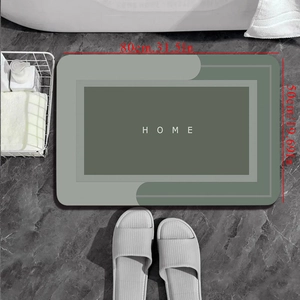 Detail showing an 80x50cm grey-green anti-slip bath mat with Home text on marble floor