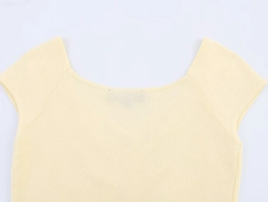 Detail view of a pale yellow knitted top featuring a U-shaped neckline and fine texture
