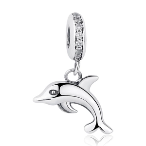 Macro shot of silver dolphin pendant with small clear crystals on a white background