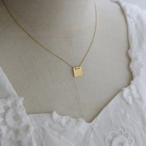 Close-up of vintage gold square pendant engraved with 1987 on a fine necklace chain