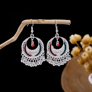 Artistic shot of bohemian crescent earrings with red beads and silver tassels on wood