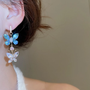 Close-up of double-layer butterfly drop earrings with blue and clear zircon crystals