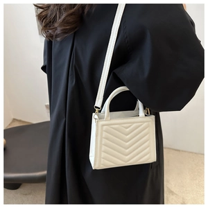 Detailed back view of a white quilted handbag with V-shaped stitching and top handle