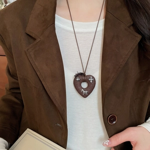 Close-up of a vintage heart pendant with metallic horse and floral details