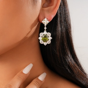 Close-up of vintage flower drop earrings with green oval gemstone and silver accents