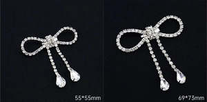 Detail showing two sizes of rhinestone butterfly brooches with crystal pendants on black background