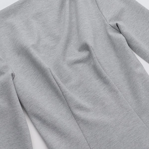 Close-up of light gray knit fabric showing fine texture and professional stitching detail