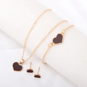 Detailed close-up of a heart-shaped gold necklace and bracelet set on a white fabric