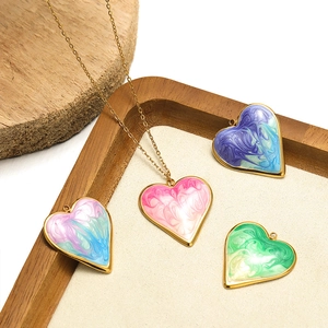 Colorful heart-shaped enamel pendants with gold metal bases on a wooden jewelry display tray