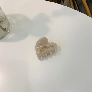 Detailed close-up of a heart-shaped acetate hair claw in elegant cream beige color