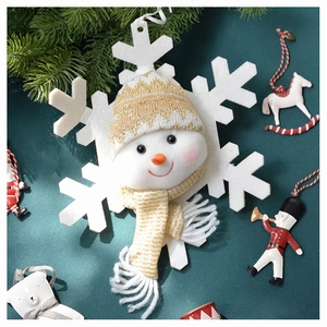 Close-up of a plush snowman snowflake ornament with a gold knit hat and festive scarf