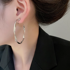 Detail of silver twisted hoop earrings showing polished metal texture and minimalist design