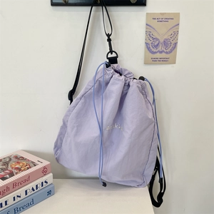 Detail of light purple nylon drawstring backpack with white sotkka embroidery and black straps