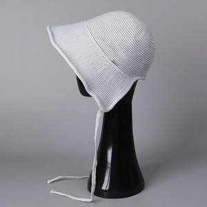 Detail of light gray knit sun hat with chin strap and wide wavy brim on model