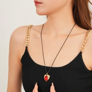 Detail of vintage gold heart necklace with a red gemstone on a female model