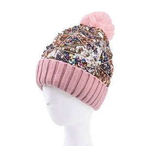 Dettaglio del berretto in maglia rosa con paillettes metalliche e pompon in ecopelliccia