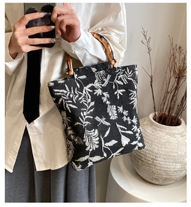 Detail of floral linen handbag featuring natural bamboo handle held by a model