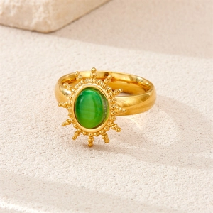 Detail of vintage 18k gold plated ring with oval green gemstone and sunburst texture