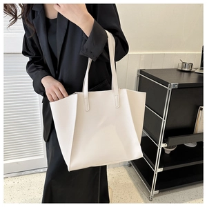 Close-up of a white leather tote bag styled with a professional black blazer outfit
