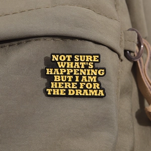 Detail of enamel pin with humor quote on canvas bag, black and yellow metal badge