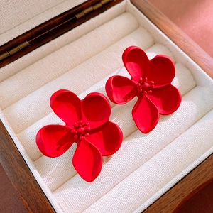 Detailed close-up of red matte flower pearl earrings placed on a dark wooden jewelry box