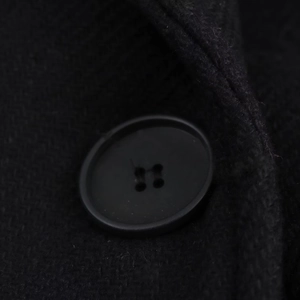 Close-up of the black woolen fabric texture and matching resin button on long coat