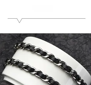 Detail of woven black leather and silver metal chain accessory on white ceramic