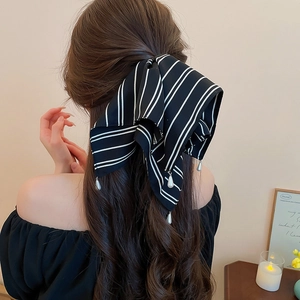 Détail d'un nœud papillon à rayures avec pendentifs en perles sur tissu satiné soyeux