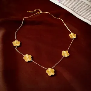 Collier en acier inoxydable doré à cinq pendentifs fleurs sur satin rouge foncé
