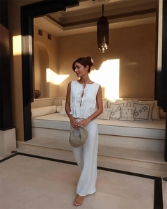 Chic white pleated sleeveless top and wide leg trousers set with a woven handbag detail