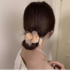Detail of beige rose flower hair clip on elegant bun hairstyle with lace texture