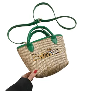 Detailed close-up of a woven straw tote with green leather straps and tiger embroidery