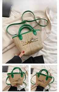 Detailed close-up of a woven straw tote with green leather straps and tiger embroidery