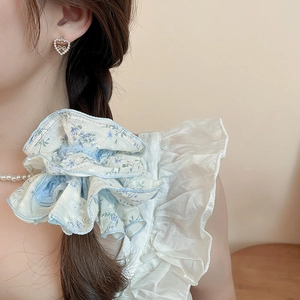 Detailed view of a light blue floral scrunchie with lace trim on a braided hairstyle