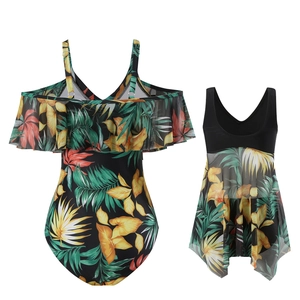 Détail du maillot une pièce noir à imprimé tropical et son vêtement de plage en maille
