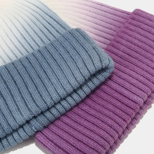 Detailed macro of ribbed knit beanies featuring unique gradient dye and folded cuff texture