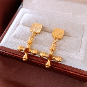 Macro shot of vintage gold cross earrings with amber bead on a velvet jewelry box